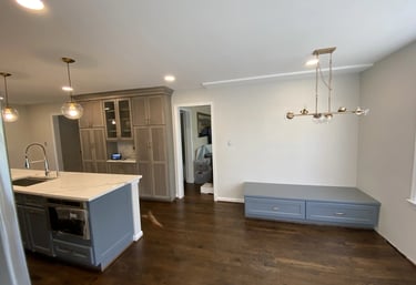 Remodeled kitchen with dark gray island, light gray pantry, and a matching gray bench.