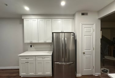 Kitchen remodel with white cabinets, stainless steel fridge, and modern white door.