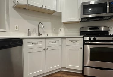 Kitchen remodel detail: white cabinets with stainless steel microwave, oven, and dishwasher.