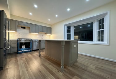 Kitchen renovation with grey cabinets, large island, and light brown LVP floor.
