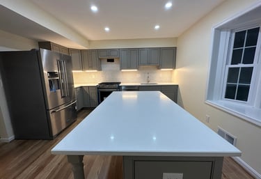 Long view of a grey kitchen remodel with large white island and light brown LVP floor.