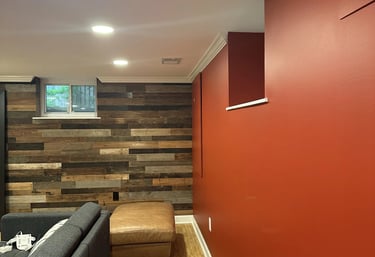 Renovated basement corner with reclaimed wood accent wall meeting deep red drywall and white crown.