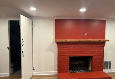 Freshly painted red brick fireplace with natural wood mantel against new matching red drywall.
