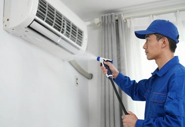 Smiling technician inspecting an air conditioning unit on a residential balcony.