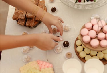 Mesa de postres elegante con un pastel estilo naked cake con frutos rojos y macarons rosas