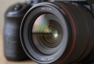 A close-up of a high-end camera lens capturing light reflections, representing photography and technical precision. The image follows a modern aesthetic with cool tones of #6E7C8B.