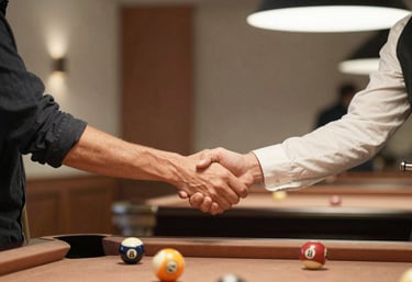 A candid photograph of two people shaking hands over a pool table after a match. They are surrounded by a warm, inviting atmosphere with soft cream and bronze accents in the background.