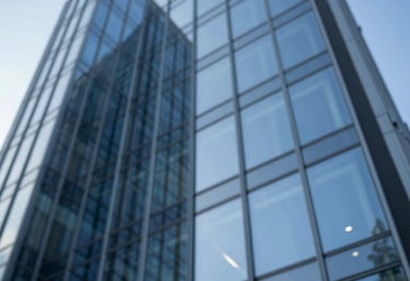 A low-angle shot of contemporary architectural glass reflecting a blue sky, symbolizing innovation and strategic clarity, incorporating #4B6587.