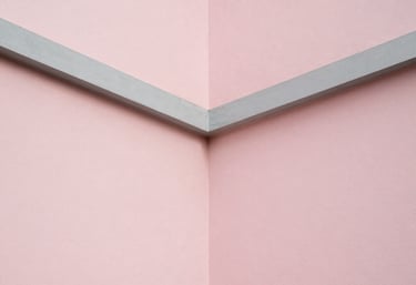 A minimalist architectural detail showing the intersection of light pink walls and clean grey lines under soft natural light.