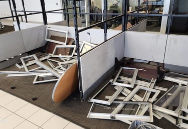 Dismantled office cubicles and metal workstation frames scattered across an office floor during a renovation.