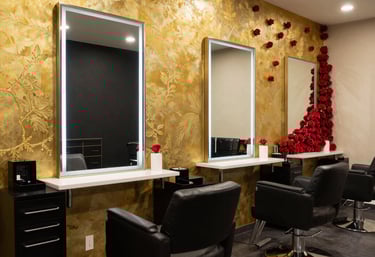 A close-up of a client smiling as a stylist carefully shapes her eyebrows with a gentle touch.