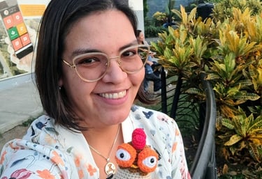 Una mujer sonriendo sosteniendo un amigurumi de gallineta