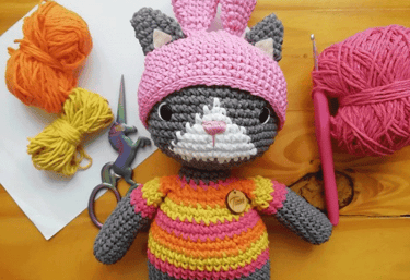 Un amigurumi de gatito con un sombrero rosa