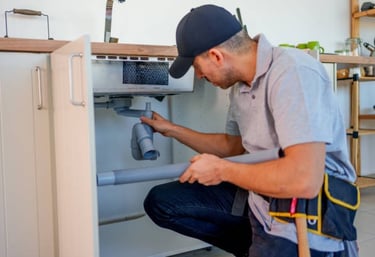 plumber working on a drain under a sink