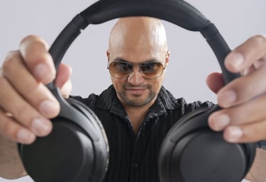 a man in a black shirt and sunglasses holding a pair of headphones