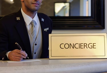 Professional hotel concierge in a formal uniform writing at a luxury service desk with a concierge sign.