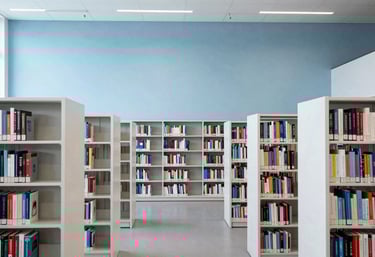 A wide shot of a minimalist, high-ceiling academic library with rows of white bookshelves in an International Academic university. Palette: Soft Sky Blue and Crisp White.