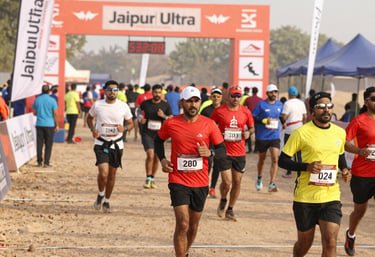 Runners crossing a desert trail with the Jal Mahal glowing in the early morning light.