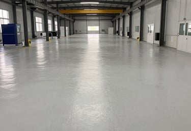 A skilled technician applying epoxy flooring in a modern industrial space.