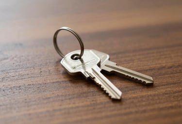 A pair of shiny silver house keys resting on a polished wooden table, softly lit to highlight textures, representing the successful acquisition of a new home.