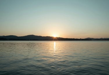 A peaceful outdoor scene of a sunset over a calm lake, representing a worry-free retirement. High-quality photography with soft #B8D3E7 and #4A7C59 color tones.