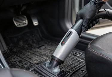 A professional detailer carefully washing a shiny car exterior under natural light.