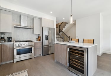 Modern luxury kitchen with stainless steel appliances, marble backsplash, and a kitchen island featuring a built-in wine