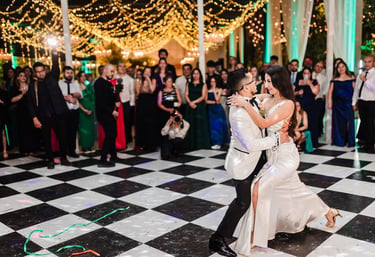 Una pareja de recién casados ​​compartiendo su primer baile en una pista de baile a cuadros.