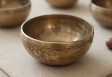 A metal Tibetan singing bowl resting on a soft beige cushion, captured with a shallow depth of field, evokes vibration and sound therapy.
