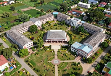 An aerial drone photograph of a beautifully landscaped rural educational complex in Chhotaudepur. The campus is green and organized, symbolizing impactful planning and development.