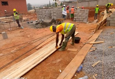 Construction workers in safety vests and hard hats building a residential structure with concrete blocks.