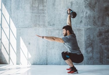 Homem vestindo roupa de academia realizando elevação do braço com Kettlebell