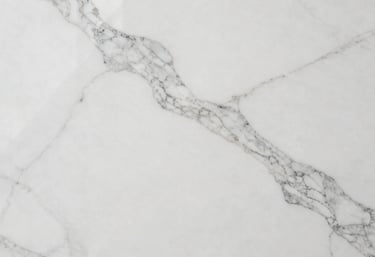 Overhead professional shot of a large polished white marble slab, showcasing delicate grey veining and a reflective clean surface, perfect for high-end flooring.