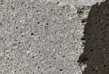 Macrophotography of the textured surface of a grey Mexican cantera stone block, highlighting its natural porous detail and authentic craftsmanship.