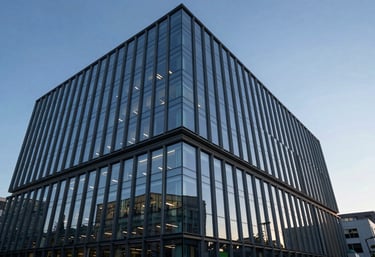 A modern, professional office building exterior with glass walls reflecting a clear Sky Blue sky at dusk.