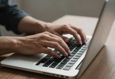 A focused shot of a person’s hands typing on a laptop in a minimalist workspace in North America.