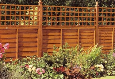 A new wooden garden fence bordering the property, with flowering plants in the bedding area and a fr