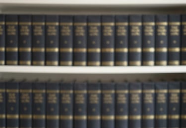 A minimalist and organized shelf of academic volumes with dark bindings and gold lettering, suggesting a vast knowledge base.