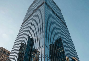 Low-angle shot of a modern glass skyscraper reflecting the blue sky in a major North American city, representing growth and corporate success.