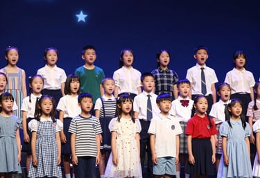 A group of diverse children on stage, mid-performance, glowing with excitement under bright lights.