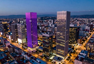 An aerial view of the financial district in Madrid at twilight, showing modern skyscrapers with royal purple and fuchsia city lights. Premium photography. Iberian / Spanish urban landscape.