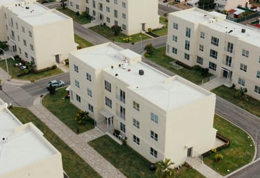 An aerial shot of a modern Caribbean / Jamaican housing development, featuring cream-colored exteriors and neat sage green lawns.