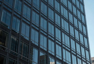 A close-up of a modern North American / US office building facade made of glass and steel, reflecting the blue sky.