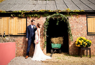 Bride and Groom outside a brick building with an archway, having a informal photoshoot at The Secret Garden wedding venue