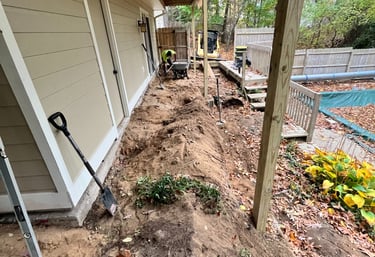 Landscaping contractor excavating dirt and grading soil for a backyard Patio project near a pool.