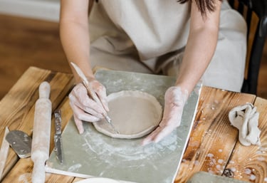 Artesana tallando para dar forma a un plato de cerámica en un taller profesional de alfarería.
