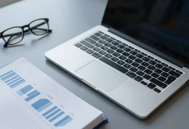 A sleek, top-down view of a professional desk with an open high-end laptop, modern glasses, and a financial planner, in a palette of #F8F9FA and #3F5B75.