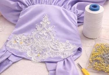 Vestido artesanal de satén morado con bordado de encaje blanco, siendo confeccionado con alfileres