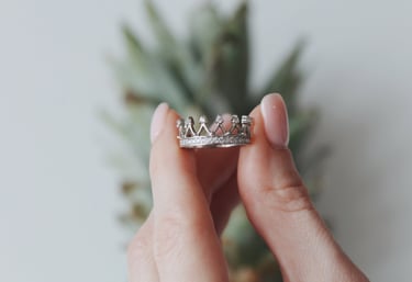 a woman's hand holding a ring with a crown