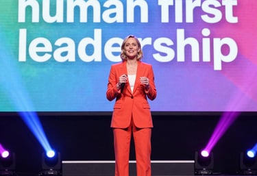 Danielle Joleigh Bennett confidently speaking on stage with vibrant lighting and engaged audience.